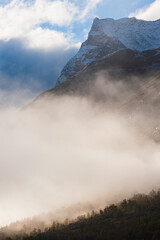 Mountain with fresh snow above mist