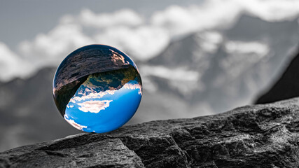 Crystal ball alpine landscape shot with black and white background outside the sphere at the famous Timmelsjoch high alpine road, Dolomites, South Tyrol, Italy