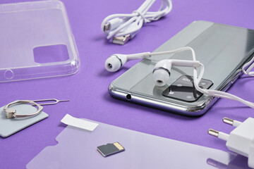 accessories for a smartphone on a purple background, protective glass, case, headphones, charger...