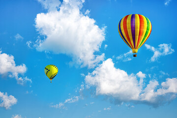 Multicolored hot air balloons on background of bright blue cloudy sky.
