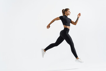 Fototapeta na wymiar Woman runner in silhouette on white background. Dynamic movement. Side view of female jogger, sportswoman in sport clothing in air, jumping or running on white studio copy space