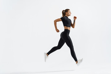 Fototapeta na wymiar Athletic fitness runner girl, silhouette of woman jogging on white background in black sportswear, wearing sport active clothing on workout, running