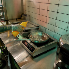Cook wearing protective gloves adding oil while frying pork or beef meat in wok pan, cooking in commercial kitchen