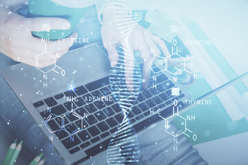 Double exposure of woman hands typing on computer and DNA hologram drawing. Medical education concept.