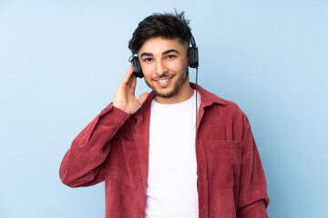 Arabian handsome man isolated on blue background listening music