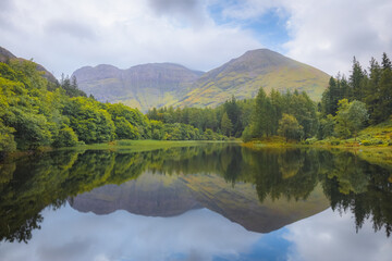 Idyllic, lush and green mountain landscape reflection on a calm Torren Lochan on a summer day at...