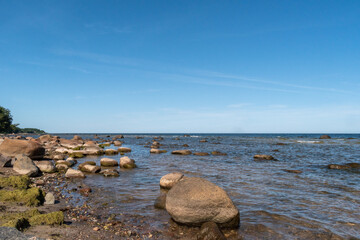 Coastline of the Baltic Sea full of big and small rocks during sunny summer day