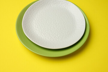 empty round white plate for main courses on a yellow background