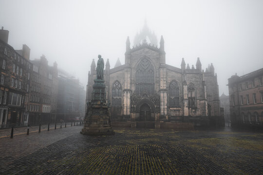 The gothic St Giles' Cathedral in moody atmospheric old town Edinburgh along the cobblestone Royal Mile in misty fog.