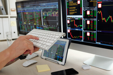 Hands of trader pushing button on keyboard hurrying to buy stocks on market