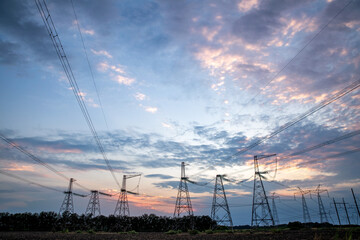 Electrical pylons and high voltage power lines at sunset background. Group silhouette of...