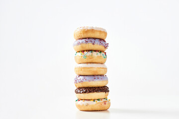 Perfect for snacking. Tower of various sweet colorful donuts with sprinkles and glaze isolated over light background
