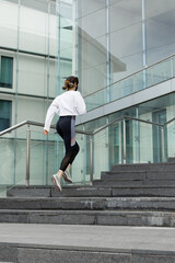 Fototapeta na wymiar Back view of sporty woman doing hiit workout running on urban outdoor stairs.