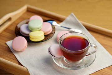 Cup of tea and colorful macaroons on a wooden tray. Morning tea and sweets