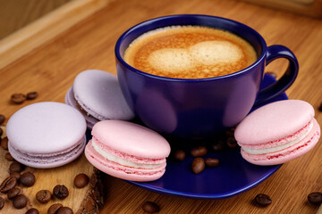 Cup of coffee, macaroons, and coffee beans on a platter on a wooden tray