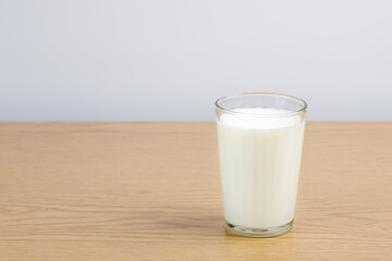A glass of milk on a wooden table on a white background