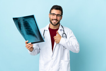 Professional traumatologist holding radiography isolated on blue background giving a thumbs up...