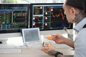 Trader eating sushi for lunch and monitoring stock market data on many computer screens in his office