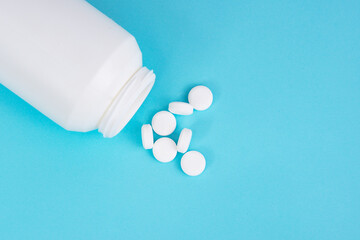 White round pills and bottle on blue background