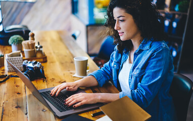 Skilled hipster girl reading text publication and browsing media content during social networking...
