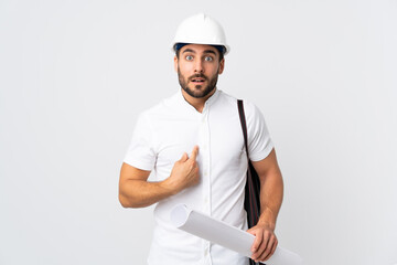 Young architect man with helmet and holding blueprints isolated on white background pointing to oneself