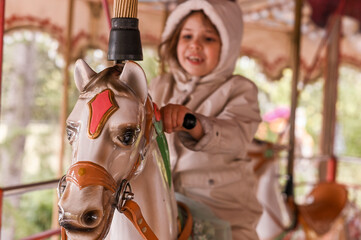 Little girl rides a carousel in an amusement park. Happy child © Marina