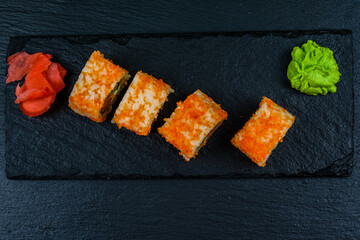 Sushi roll philadelphia with salmon, rice, cheese, cucumber, avocado and caviar on a slate board. Japanese food. Top view