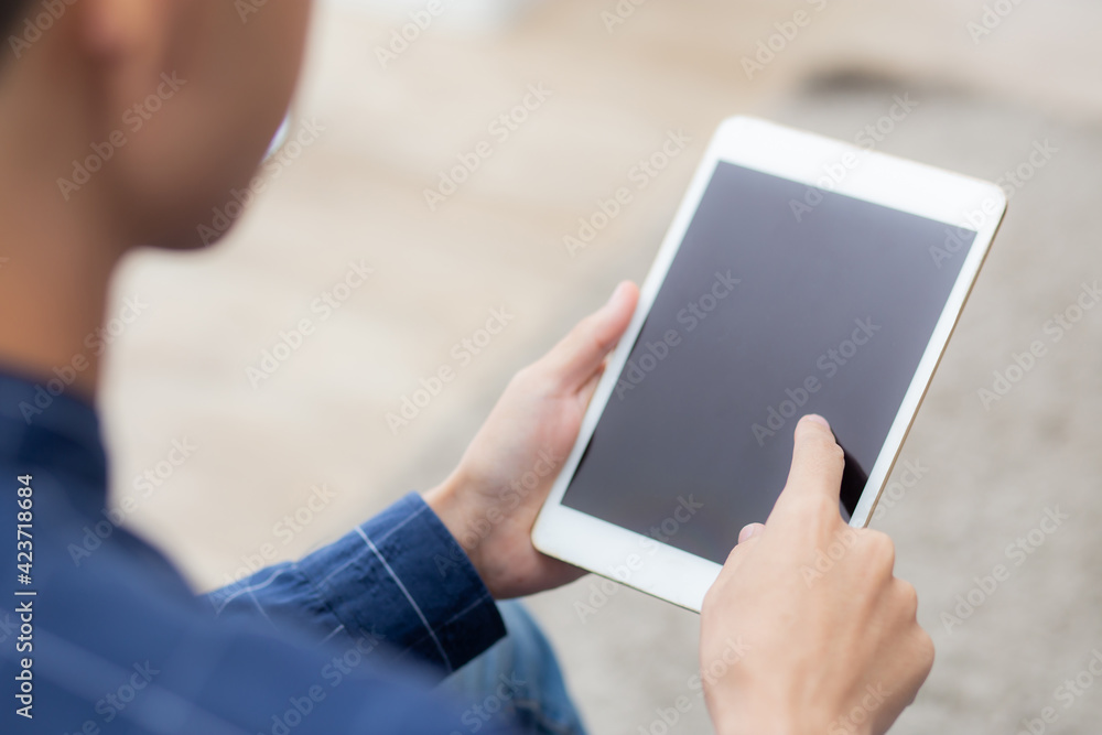 Poster closeup young asian man sitting and using mockup of tablet computer with display blank screen on sof