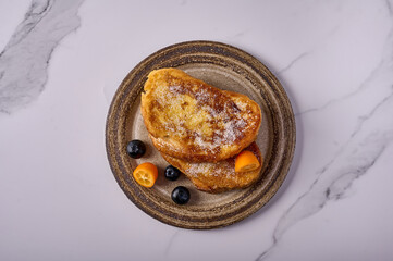 Spanish torrijas or French toast with kumquats and blueberries on marble background. Popular dessert for Christmas, Easter or Pascua. Top view