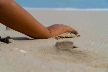 boy's hand on beach while playing in the send