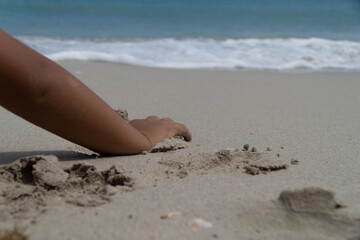 boy's hand on beach while playing in the send