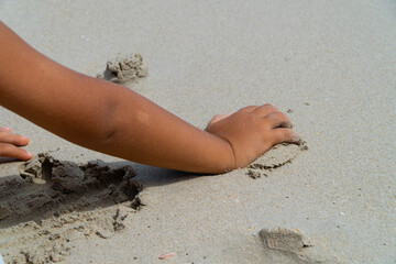 boy's hand on beach while playing in the send