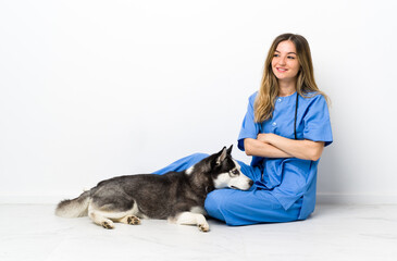 Veterinary doctor with Siberian Husky dog sitting on the floor laughing