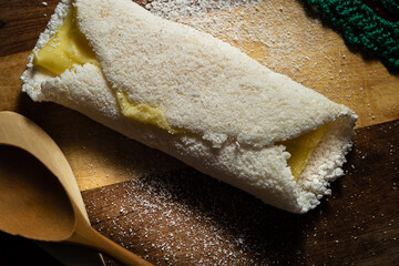 Tapioca recheada com mussarela sobre uma tábua de madeira.