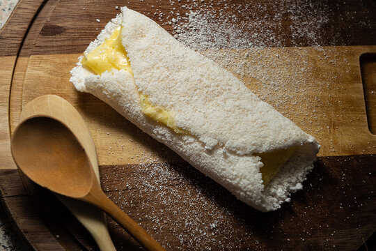 Tapioca recheada com mussarela sobre uma t&aacute;bua de madeira.
