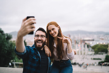 Naklejka premium Cheerful spouse 20s smiling at front cellular camera enjoying journey trip for travelling togetherness, joyful male and female best friends shooting influence vlog video via mobile application
