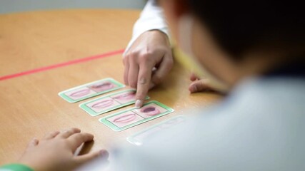 Teacher and students with specific needs of educational support. Little children learn how to pronounce. Inclusive school treating disabled children with needs.