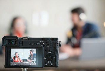 Image of people in headphones having an interview on radio and shooting it on camera