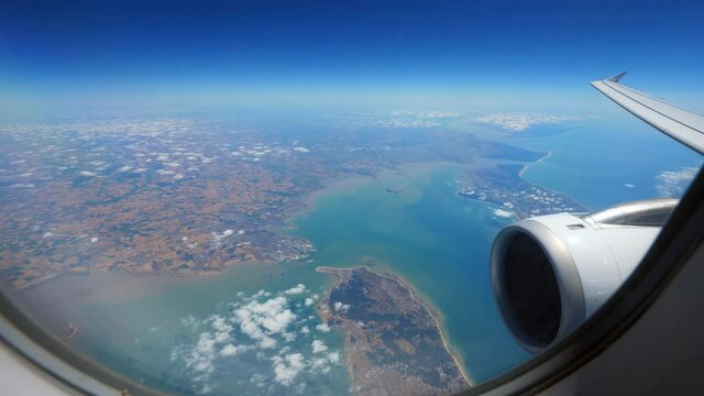 Look out through airplane window to Passage of Antioch between Isle of Rhe and Oleron Island, Bay of Biscay on Atlantic Coast of France. Jet liner engine and wing on right side at foreground