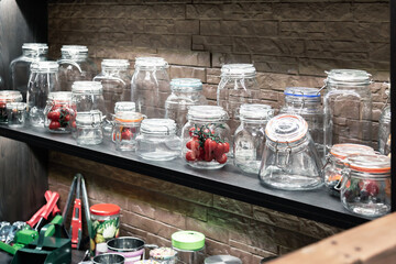 Products and accessories for home canning. Various glass jars on a shelf in a shop window on sale