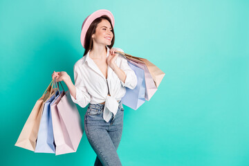 Photo of cute charming lady wear white shirt headwear holding bags looking empty space isolated turquoise color background