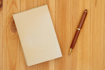Blank old paper notepad with pen on wood desk