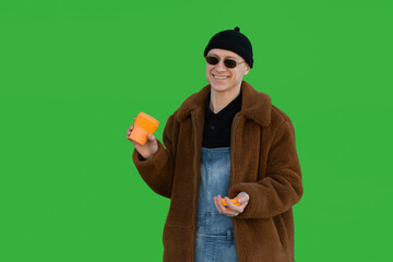 Fototapeta na wymiar Smiling a handsome man in sunglasses holding an orange reusable cup