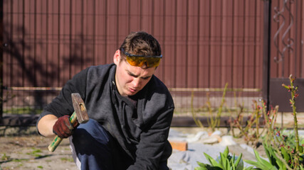 Defocus young construction worker in yellow glasses wrinkled forehead removing irregularities on...