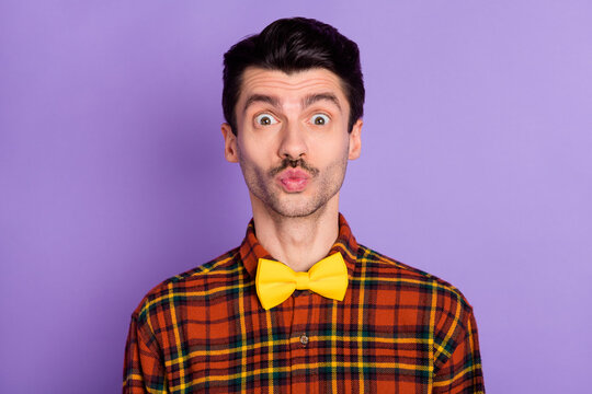 Photo of funny attractive young guy wear plaid shirt sending kiss isolated violet color background