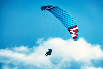 Paraglider flying over the mountains. Active people enjoying in extreme and adrenalin sports.