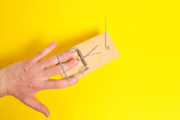 Man hand was caught in a mousetrap on a yellow background.Concept, risks, and failures.
