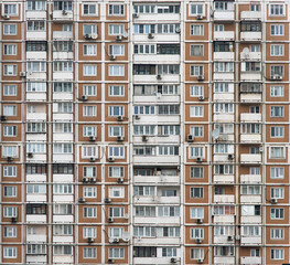 The facade of a multi-storey residential building with many windows. Old houses made of precast concrete. Cheap apartments