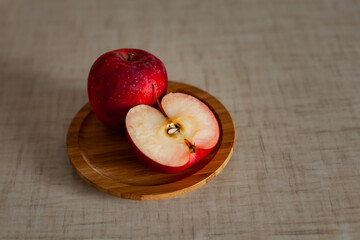 large horizontal photo. Red apple on a wooden plate. Half a red apple on a wooden tray. Vitamins. Seasonal fruits. Russia. Autumn time. Organic food. Diet. Healthy foods.