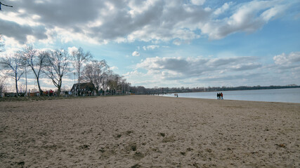 Ludzie spacerujący brzegiem jeziora w czasie wiosennego popołudnia. Na niebie pięknie chmury © Krzysztof